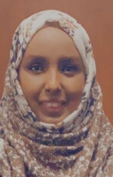 Photo of Idil facing forward.  Idil is wearing a white with patterns Hijab.